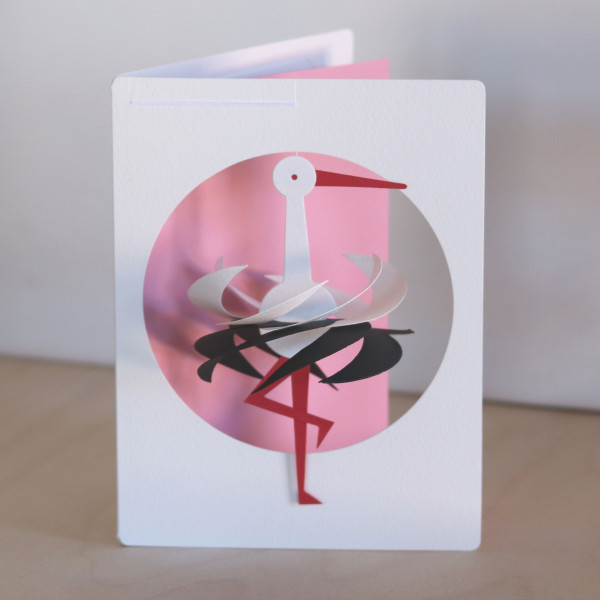 Kleiner Storch als Mobile in Postkarte vor rosa Hintergrund